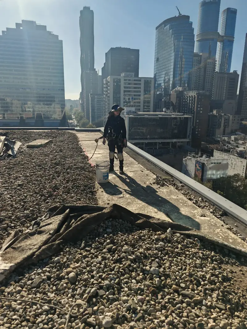 A Tower Window Cleaning rope-access technician in harness on a Melbourne CBD rooftop during a make-safe job